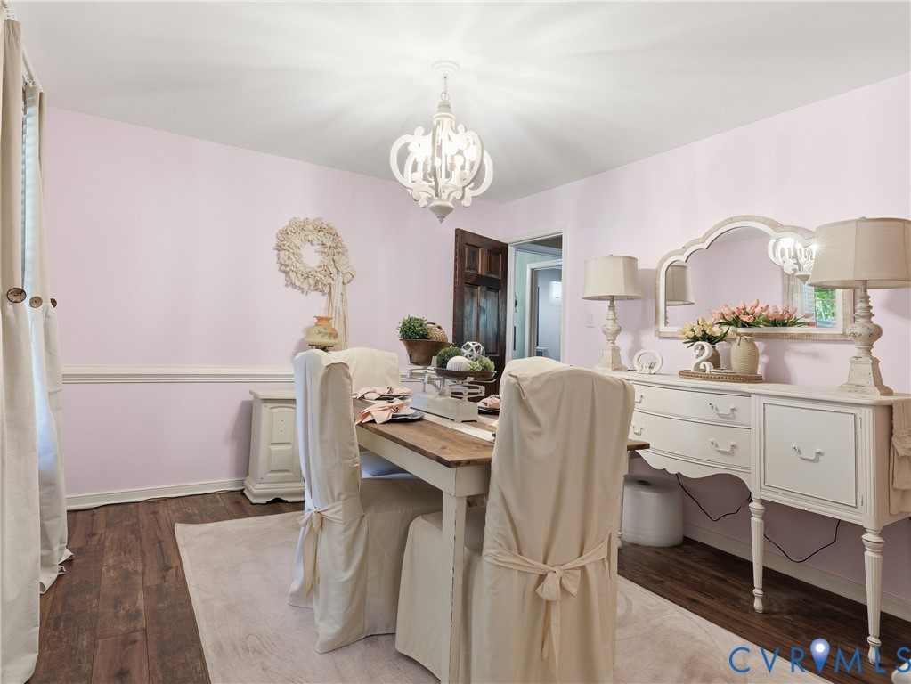Dining area featuring wood-finish flooring, chair rail molding, and a decorative chandelier