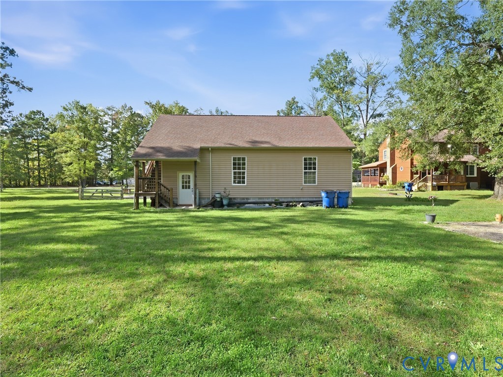 Expansive lot featuring mature trees, a gable roof structure, horizontal siding, and a wooden elevated deck