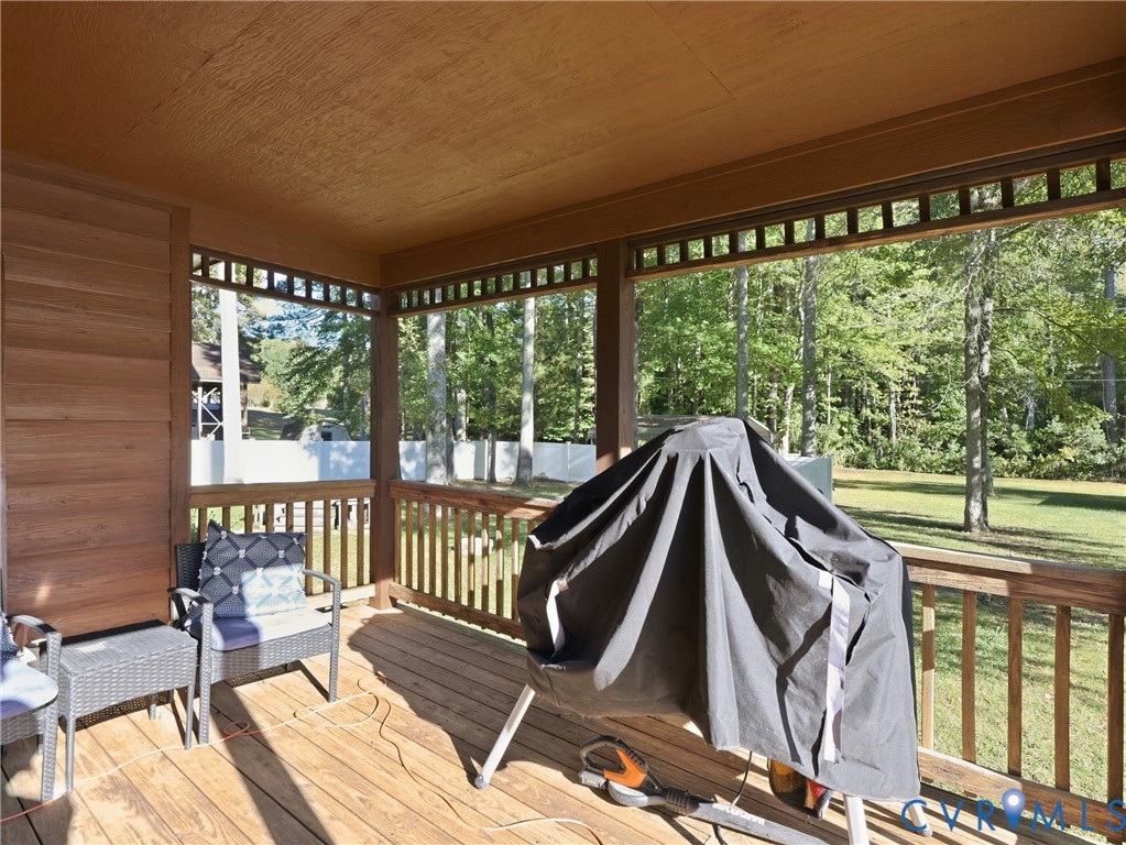 Covered wooden deck featuring horizontal wood-plank siding, decorative lattice trim, and wooden railing