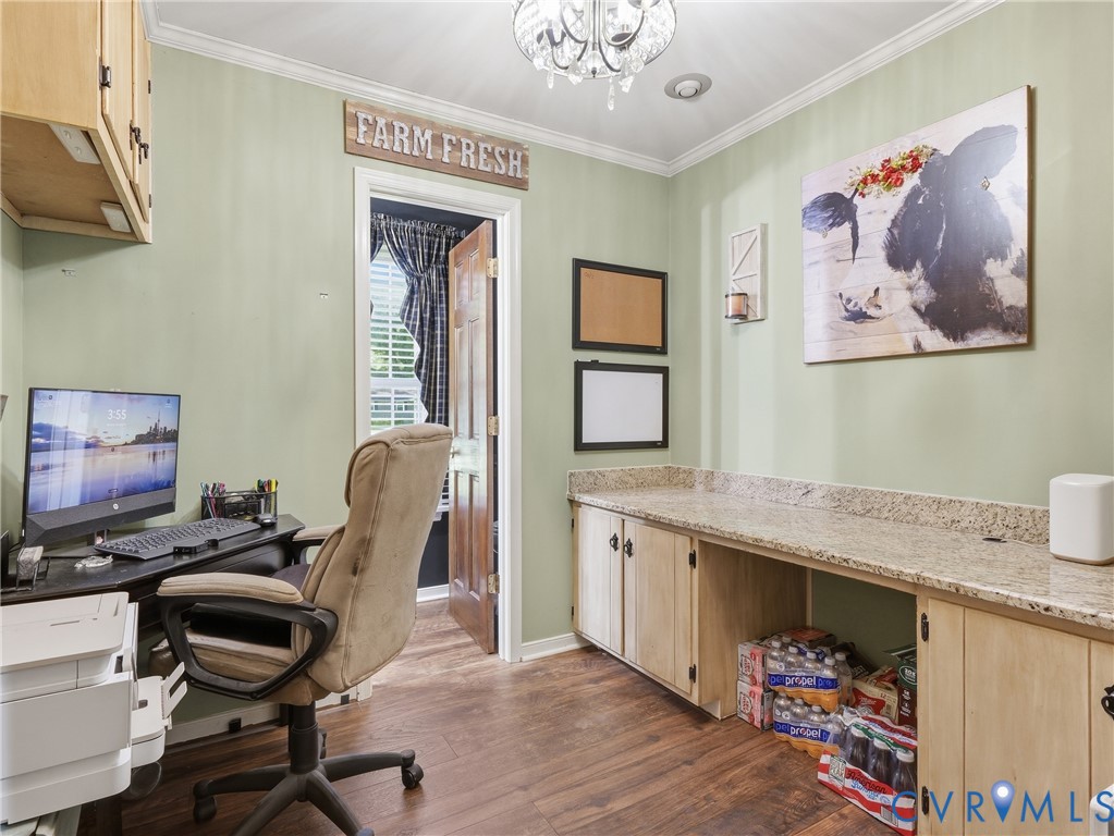 Built-in cabinetry with stone-finish countertops, wood-finish flooring, and crown molding under a decorative multi-light chandelier