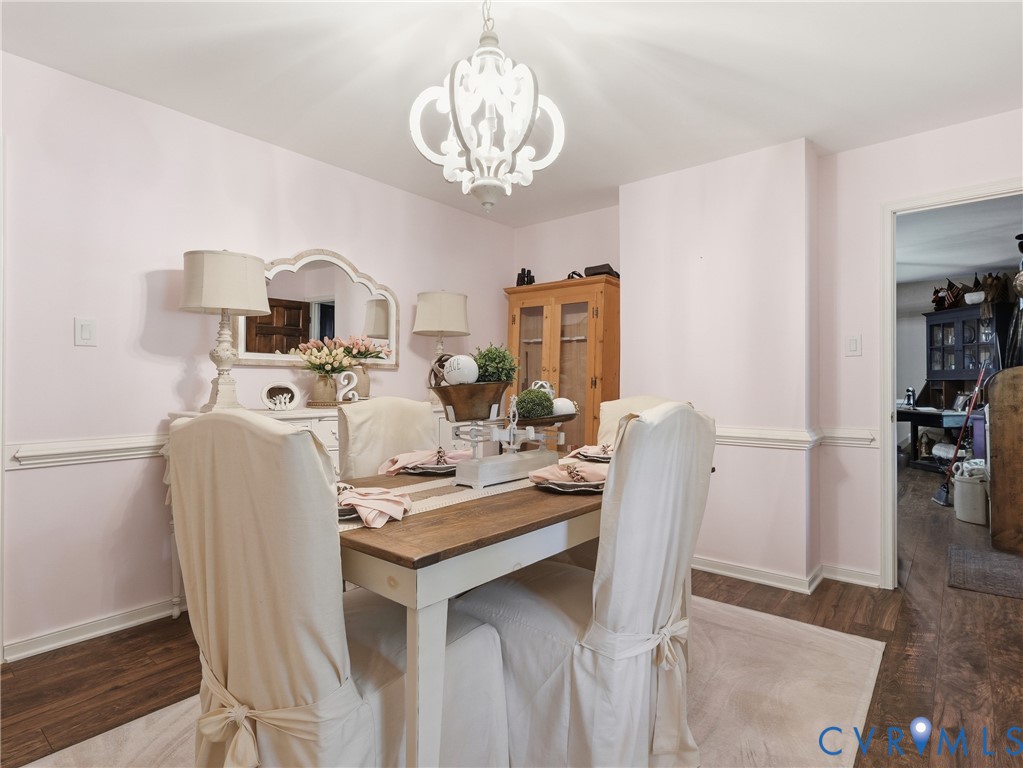 Dining area featuring decorative chair rail molding, wood-finish flooring, and a multi-arm chandelier