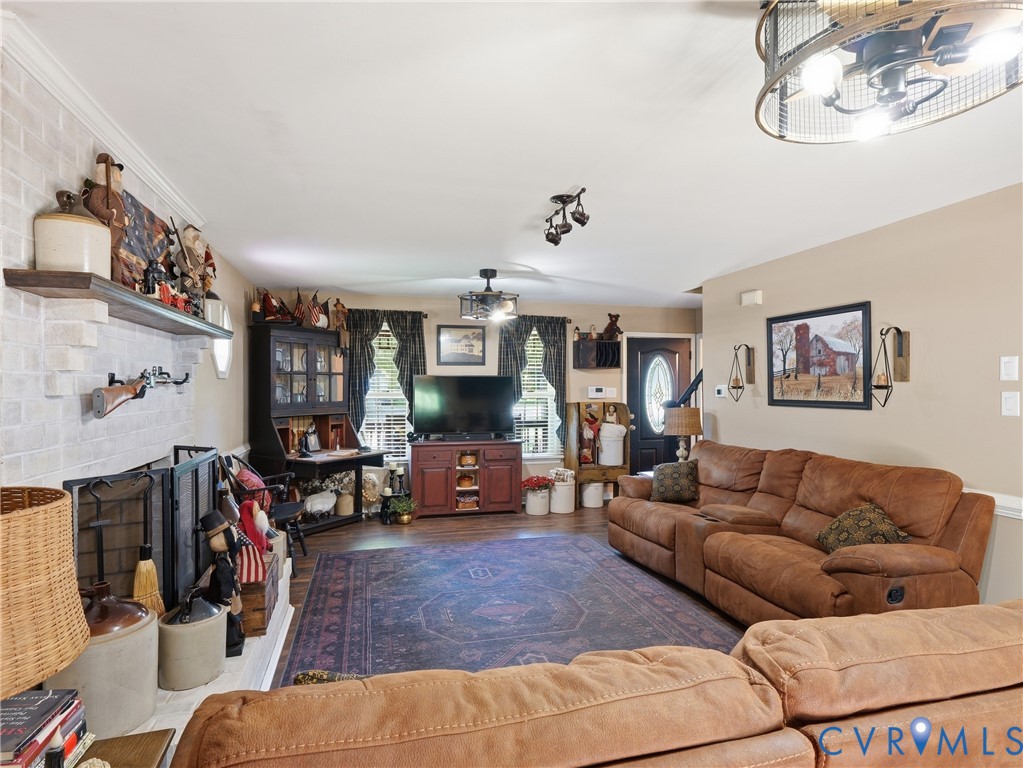 Living area featuring a floor-to-ceiling brick fireplace with a custom wood mantel, wood-finish flooring, and drum-style ceiling light fixtures