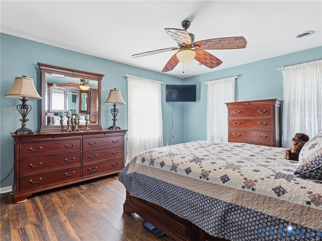 Wood-finish flooring, multi-pane windows with window treatments, and a central ceiling fan with integrated lighting