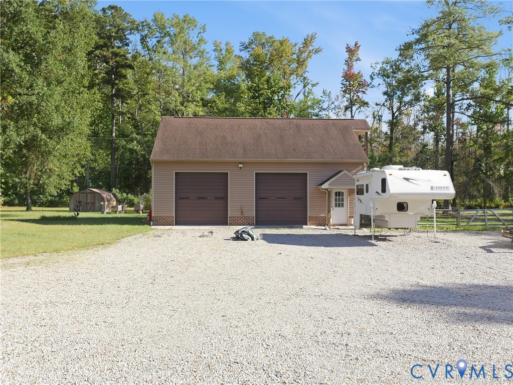 Detached two-bay garage featuring a pitched shingle roof, neutral siding, and a gravel driveway Detached two-bay garage featuring a pitched shingle roof, neutral siding, and a gravel driveway