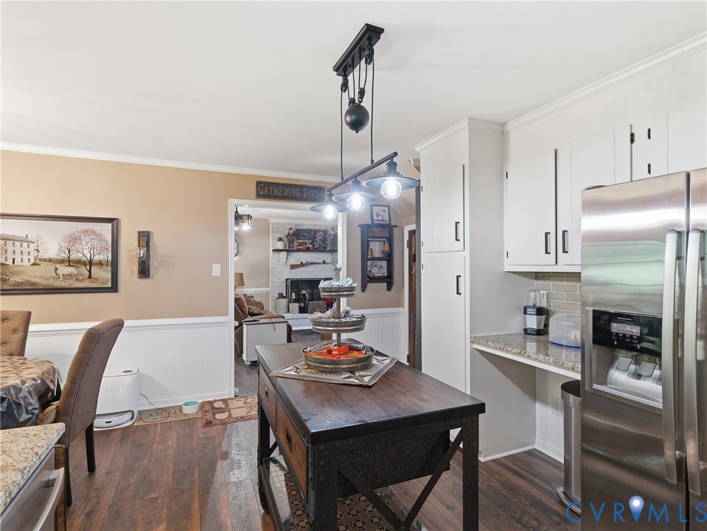 Kitchen featuring white cabinetry, stone-finish countertops, stainless steel refrigerator, pulley-style overhead pendant lighting, and wood-finish flooring