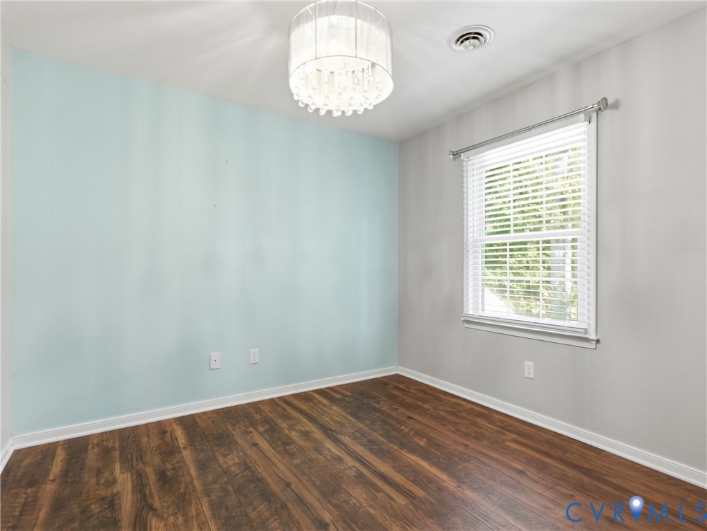 Wood-finish flooring, accent wall, and tiered crystal drum chandelier with an attached window featuring horizontal blinds