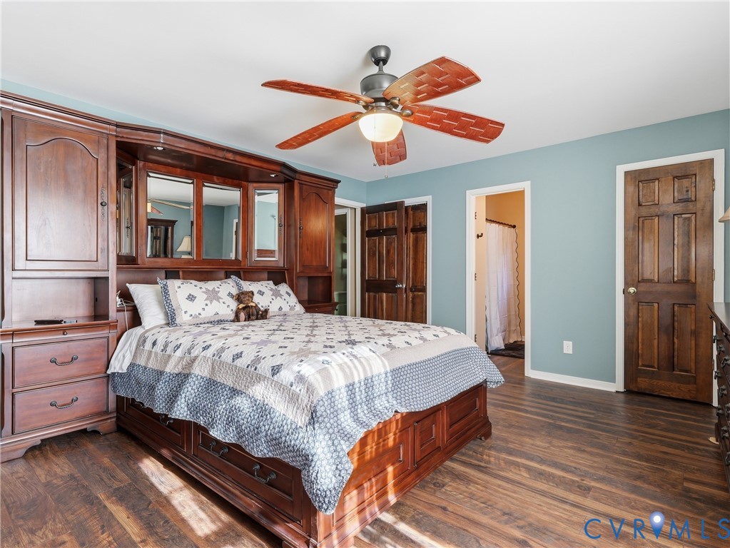 Built-in wood cabinetry with mirror accents, wood-finish flooring, six-panel wood doors, and a ceiling fan with integrated lighting