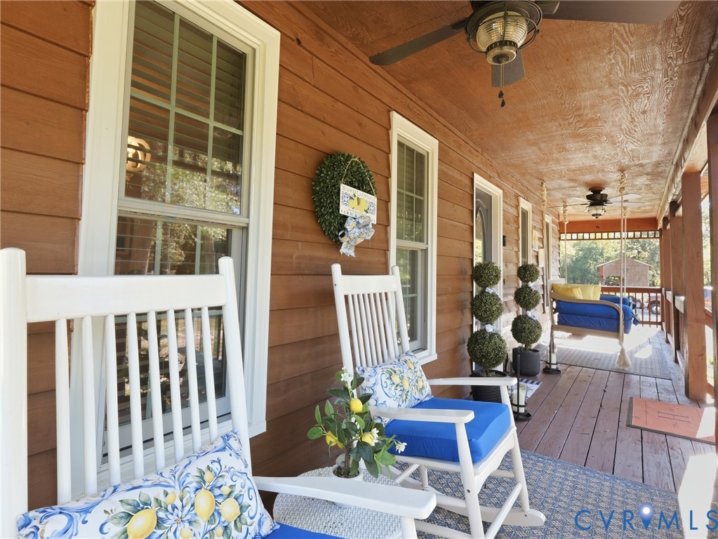 Covered front porch featuring wood-plank siding, wood-finish flooring, and two ceiling-mounted fans