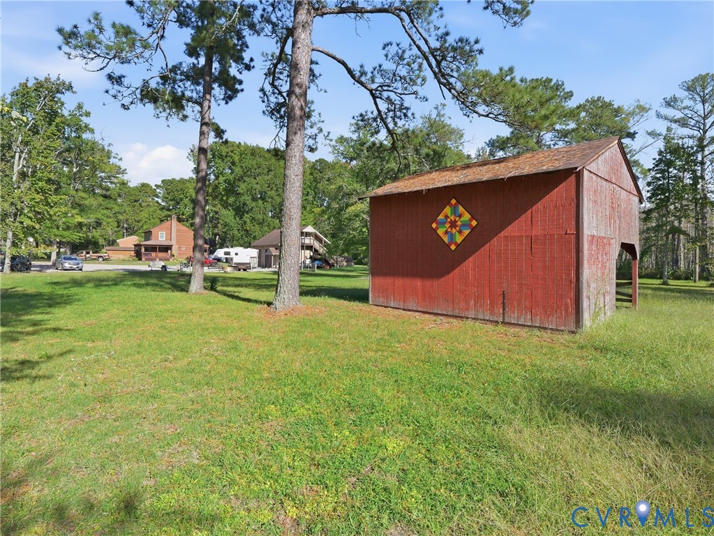 Rustic barn featuring board-and-batten siding, a gable roof, and mature trees on an expansive, open lot
