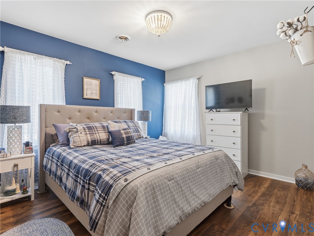 Room featuring wood-finish flooring, a bold blue accent wall, and a decorative semi-flush mount ceiling fixture