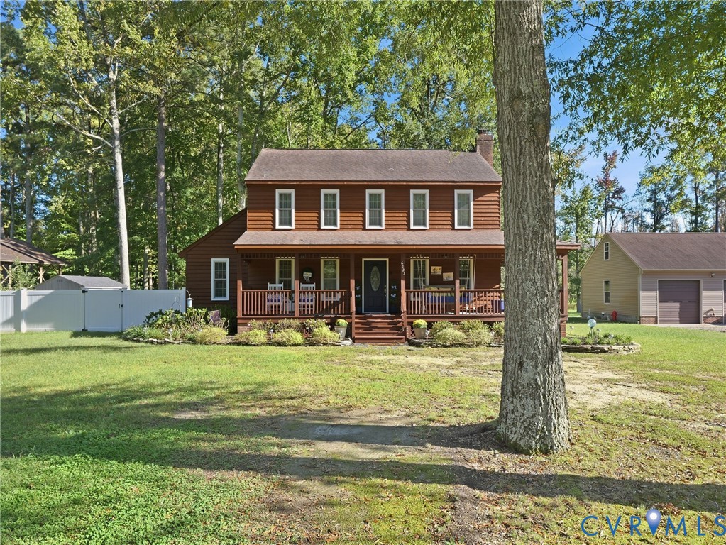 Two-story wood siding exterior featuring a covered front porch, stone-bordered landscaping, and a detached garage Two-story wood siding exterior featuring a covered front porch, stone-bordered landscaping, and a detached garage