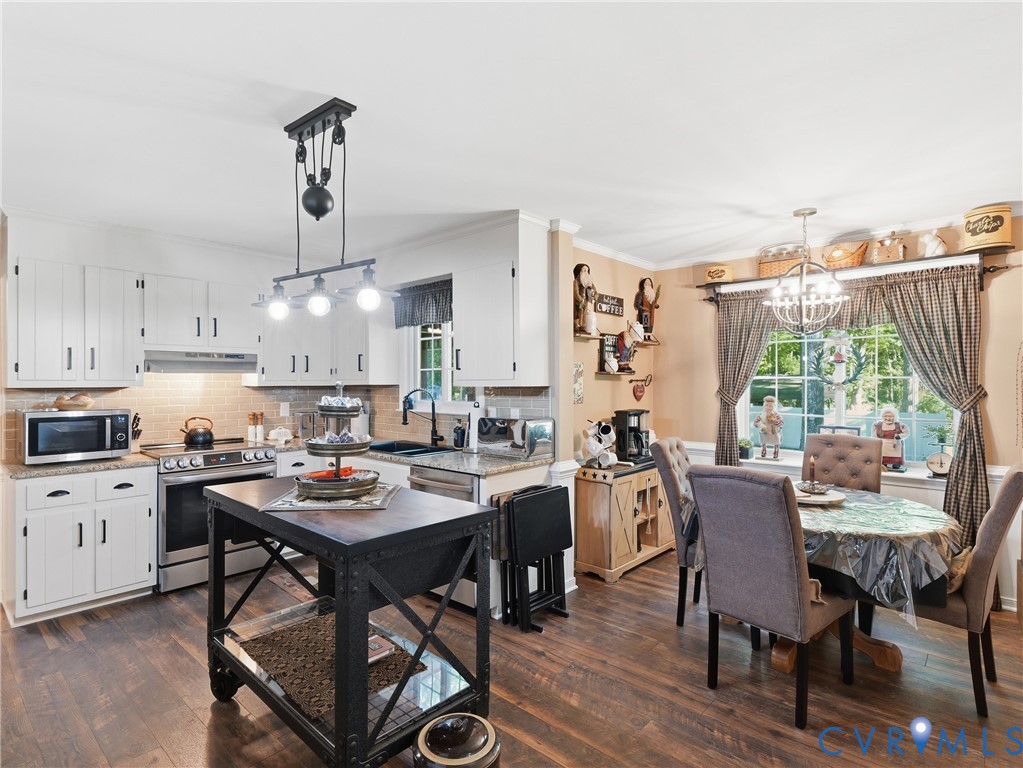 Kitchen featuring white shaker-style cabinetry, stone countertops, industrial-style pulley pendant lighting, and wood-finish flooring