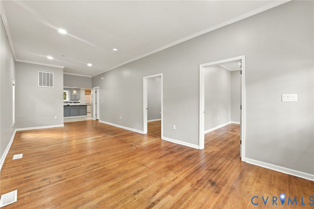 Wood-finish flooring throughout, recessed ceiling lighting, light grey wall paint, white trim, and open doorways