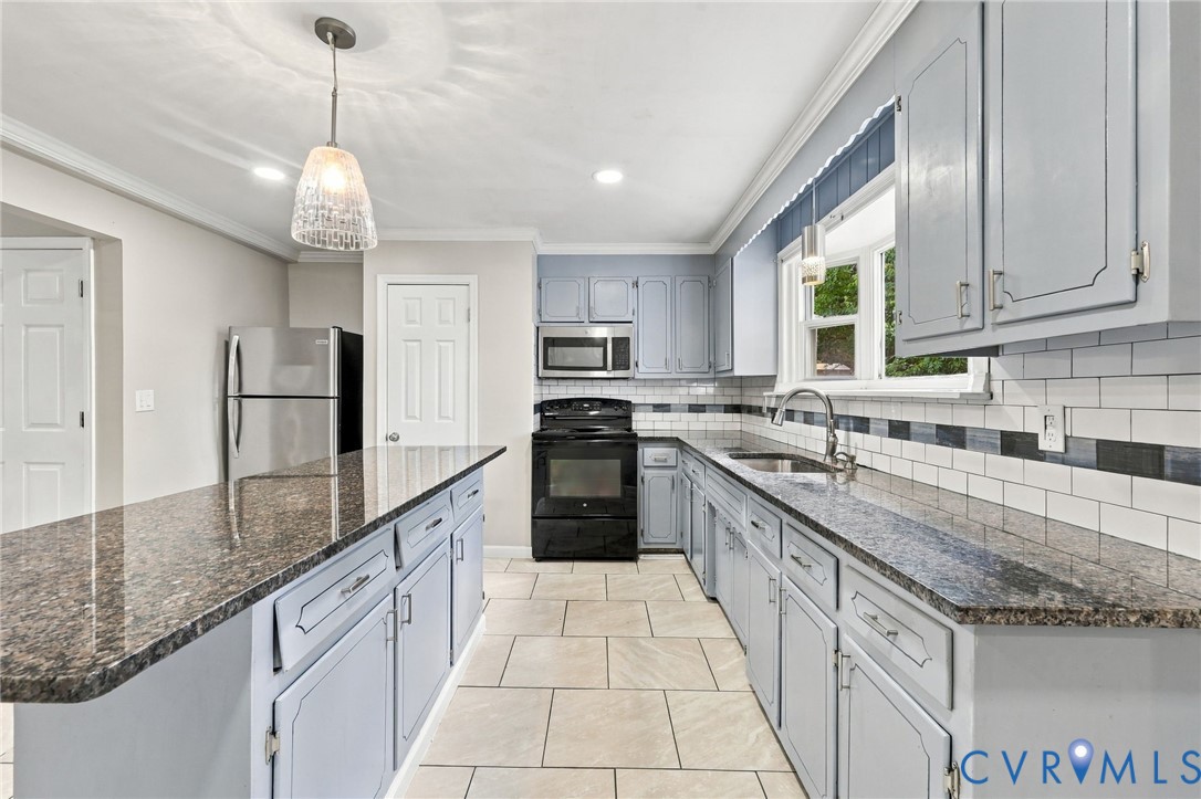 Kitchen featuring light blue cabinetry, stone countertops, a subway tile backsplash, and a central island with pendant lighting