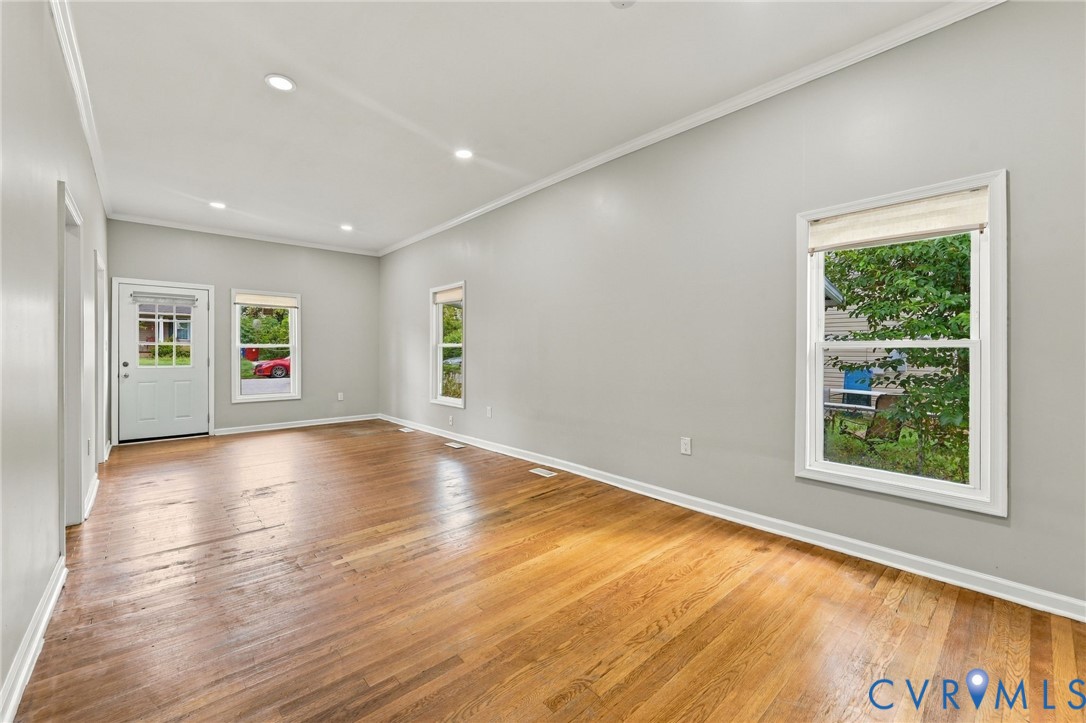 Hardwood flooring, recessed lighting, multiple windows, and a white entry door