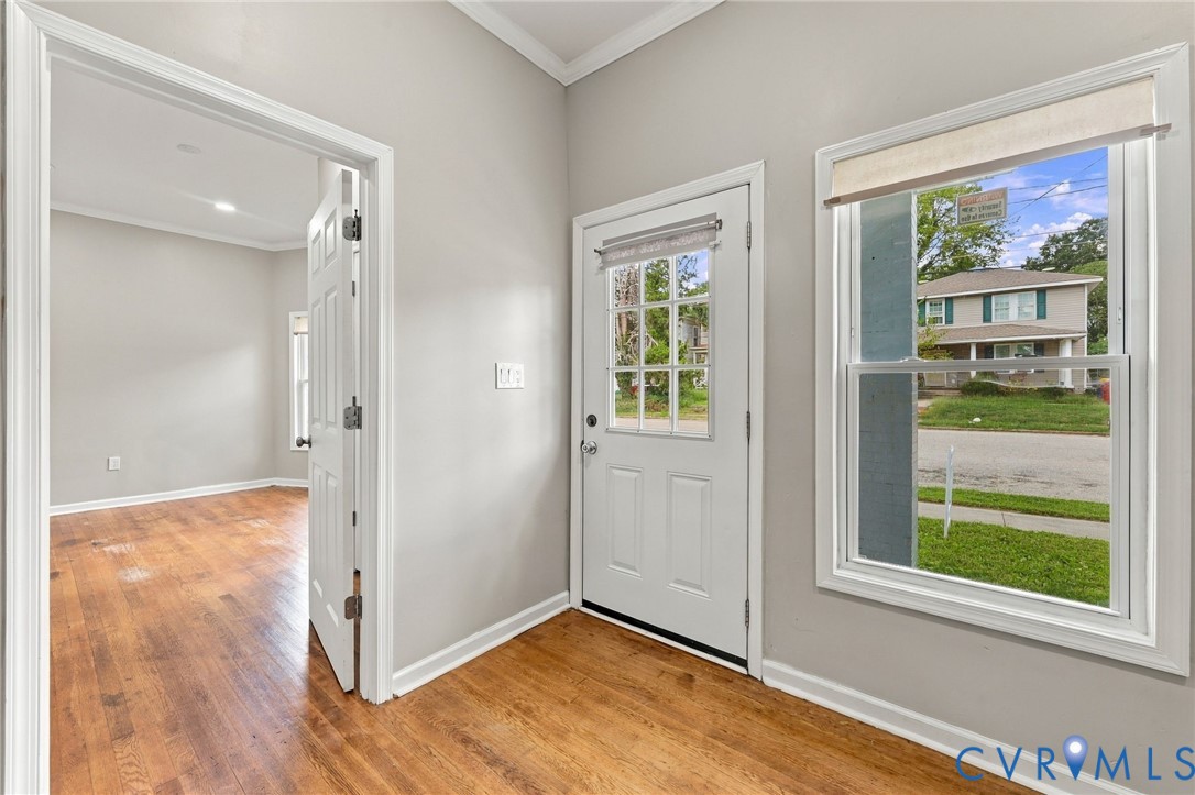 Hardwood flooring, light gray wall finishes, white trim, and a white paneled door with glass inserts