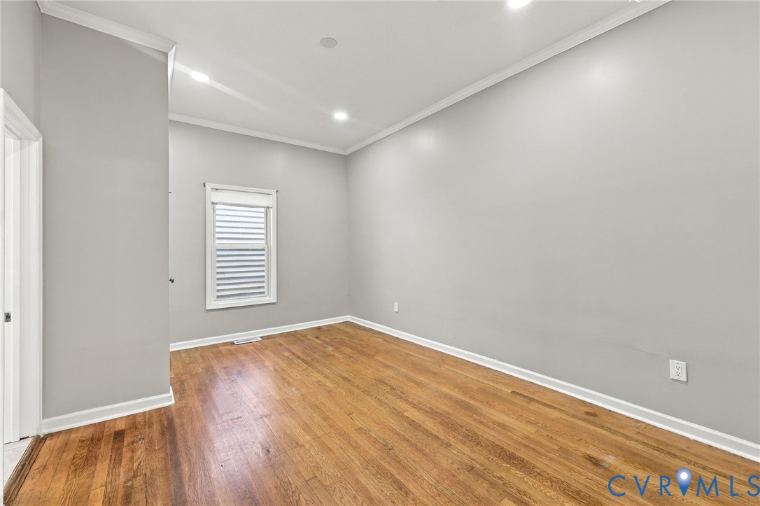 Hardwood flooring, recessed lighting, crown molding, a window with blinds, and a white interior door