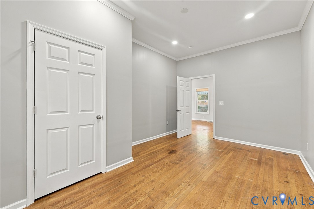 Wood-finish flooring, recessed lighting, crown molding, and white trim accents