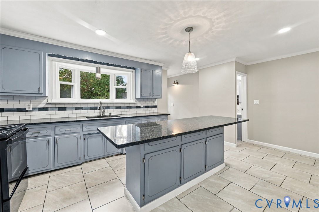 Kitchen featuring gray cabinetry, a central island with a dark countertop, white subway tile backsplash, and light-toned floor tiles