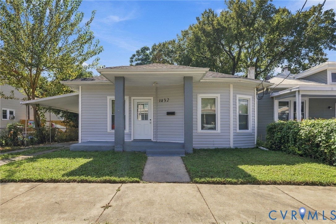 Light-colored siding exterior with a covered front porch, carport, and a concrete pathway Light-colored siding exterior with a covered front porch, carport, and a concrete pathway