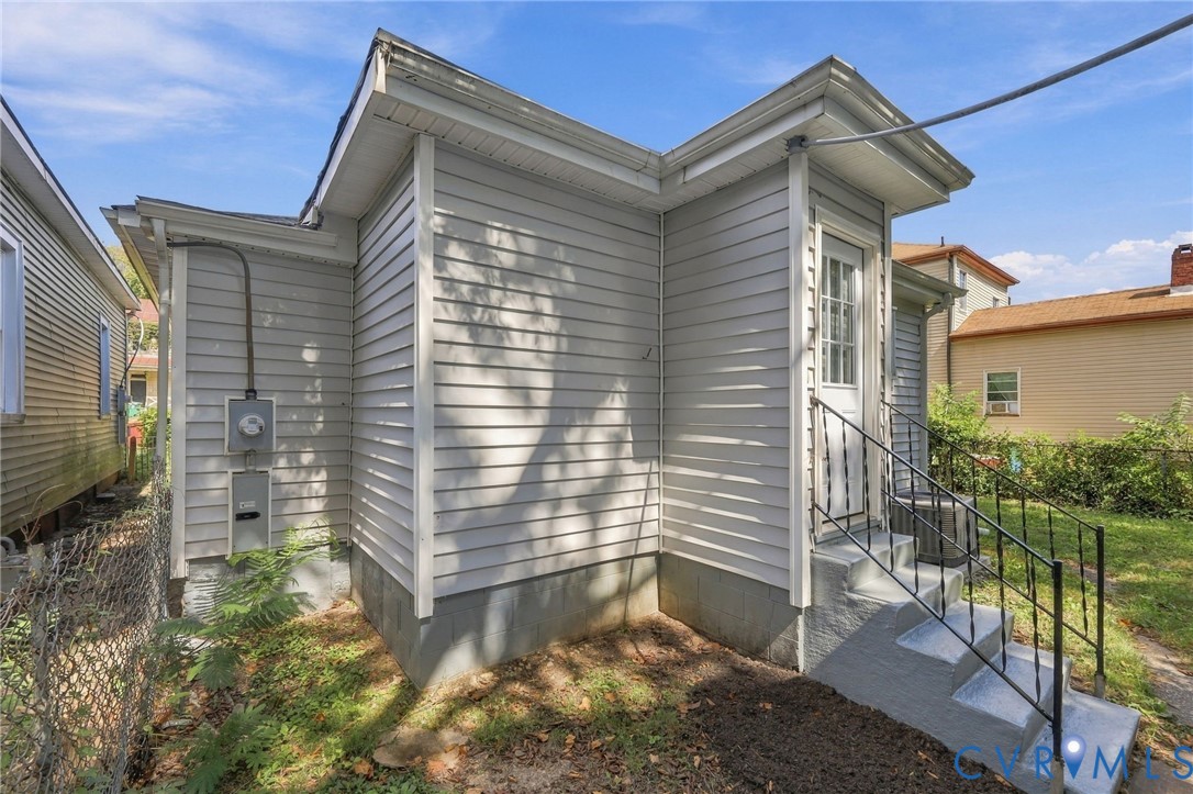 Grey siding exterior with white trim, concrete steps, and black metal handrails
