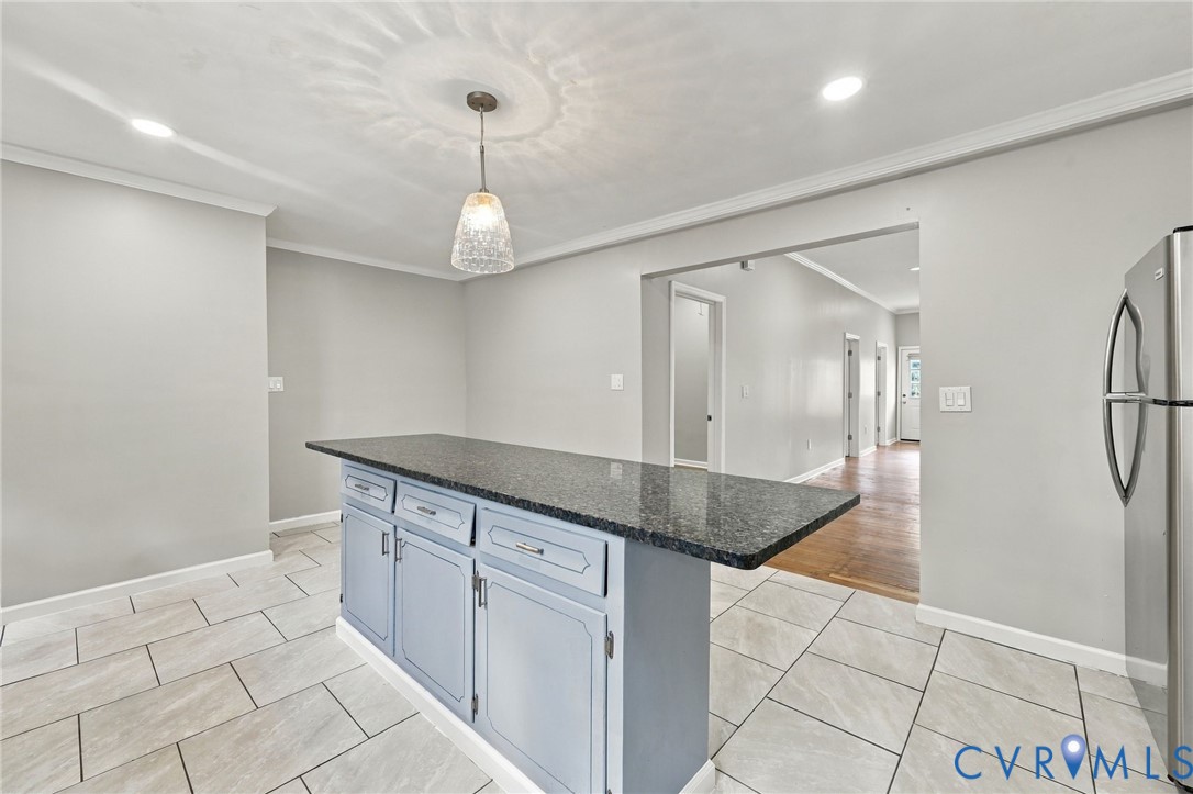 Kitchen island with a dark countertop, light blue cabinetry, and chrome hardware
