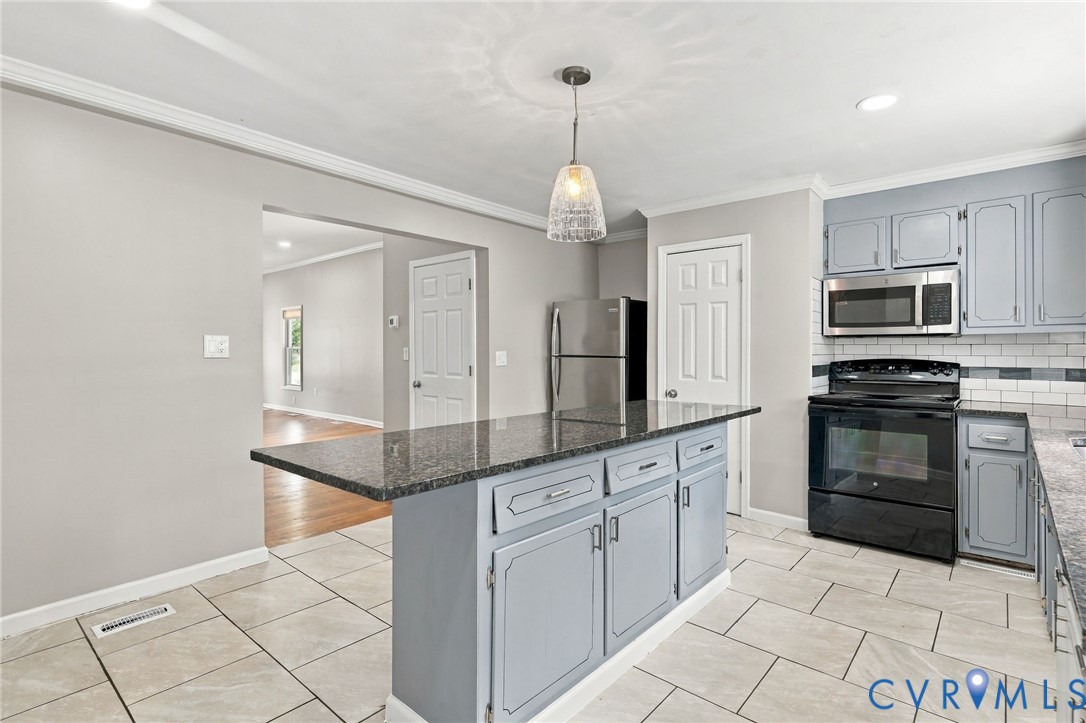 Kitchen featuring an island with stone countertop, tile flooring, stainless steel appliances, and a tiled backsplash