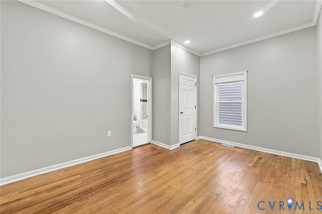 Hardwood flooring, crown molding, recessed lighting, white trim, and a paneled interior door