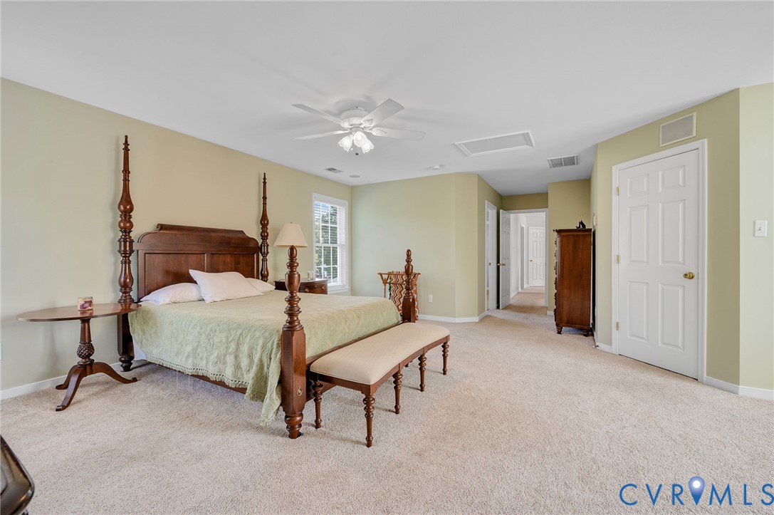 Expansive room featuring light-colored carpeting, multiple doorways, and a flush-mount ceiling fan