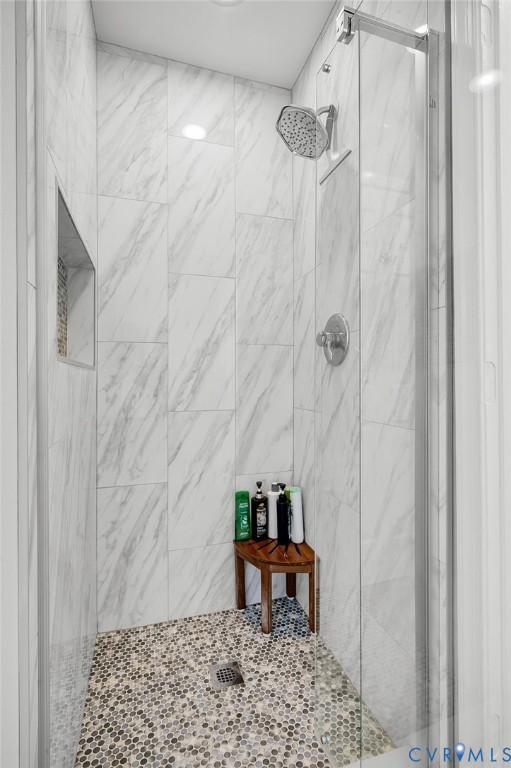 Walk-in shower with full-height wall tiling, pebble-finish floor, and a built-in shower niche
