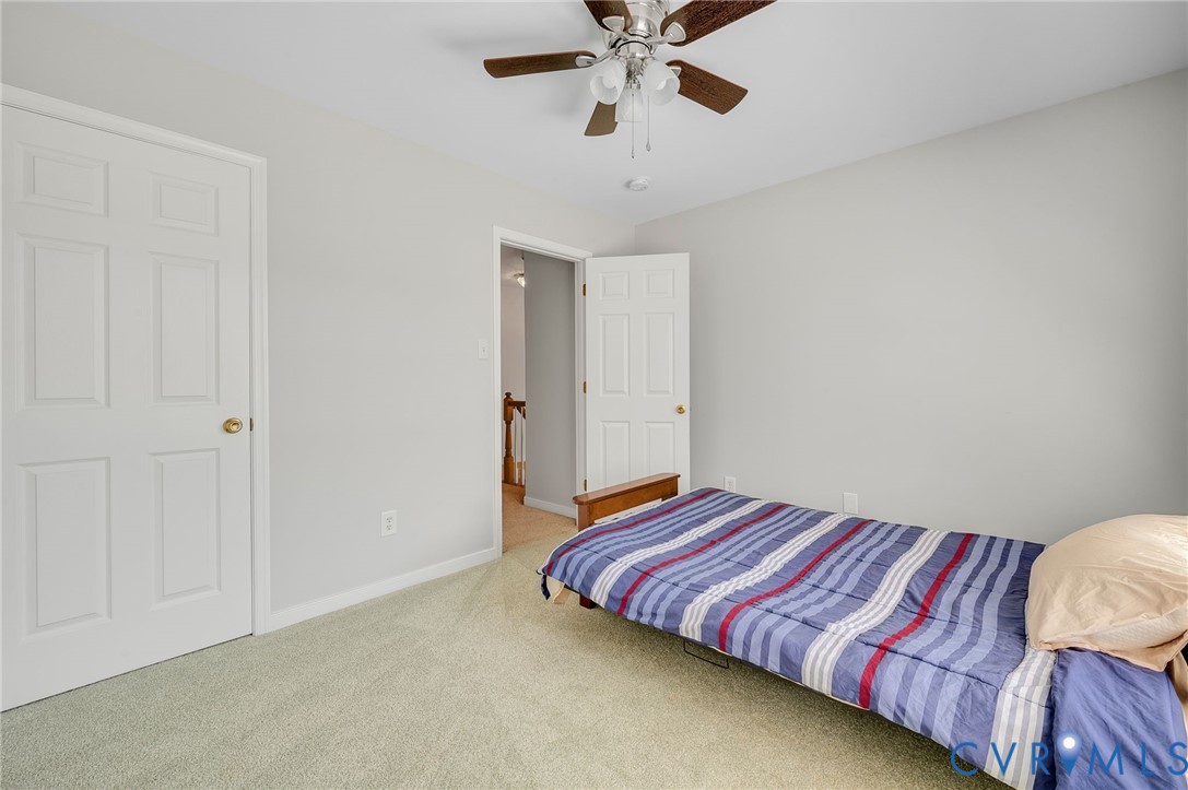 Pale green carpeting with white baseboards and a ceiling fan with light fixture