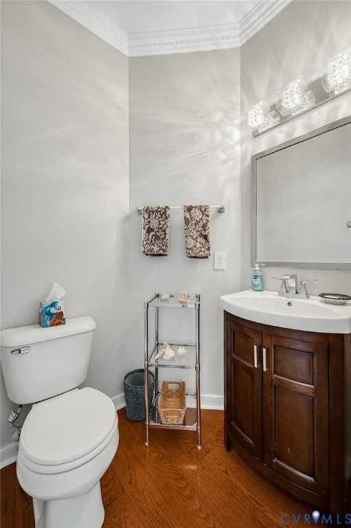 Wood-finish flooring with a white toilet, dark wood-finish vanity with an integrated sink, and an ornamental light fixture