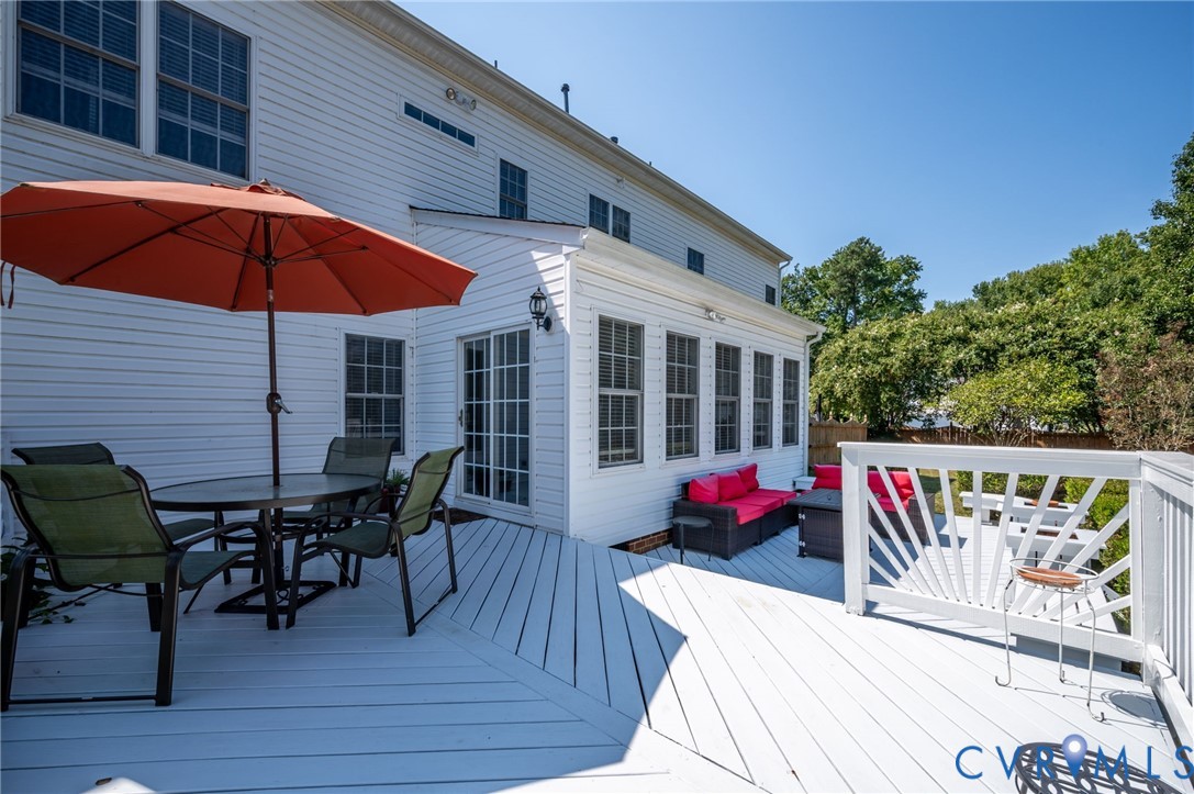 Expansive white painted deck with a sunroom addition and white siding
