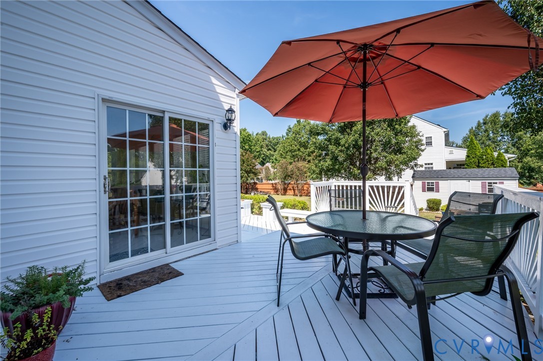 White exterior siding, sliding glass door, outdoor deck, and outdoor lighting fixture