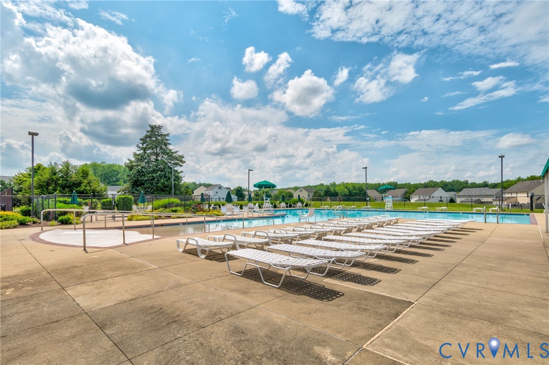 Expansive concrete pool deck with a large swimming pool, integrated spa, and surrounding landscaping