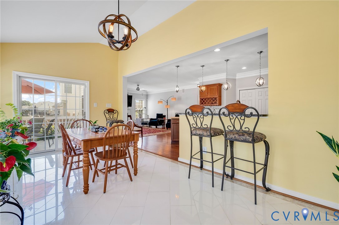 Vaulted ceiling with an orb chandelier, white tile flooring, and a sliding glass door