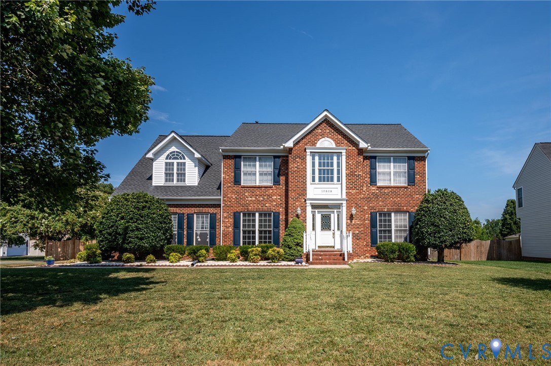 Brick facade with dark shutters, gabled roofline, and white trim accents