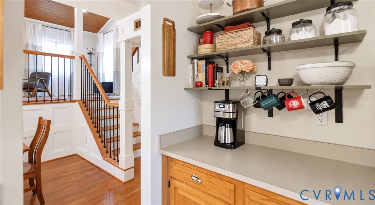 Hardwood flooring, white wainscoting, and a staircase with black iron balusters
