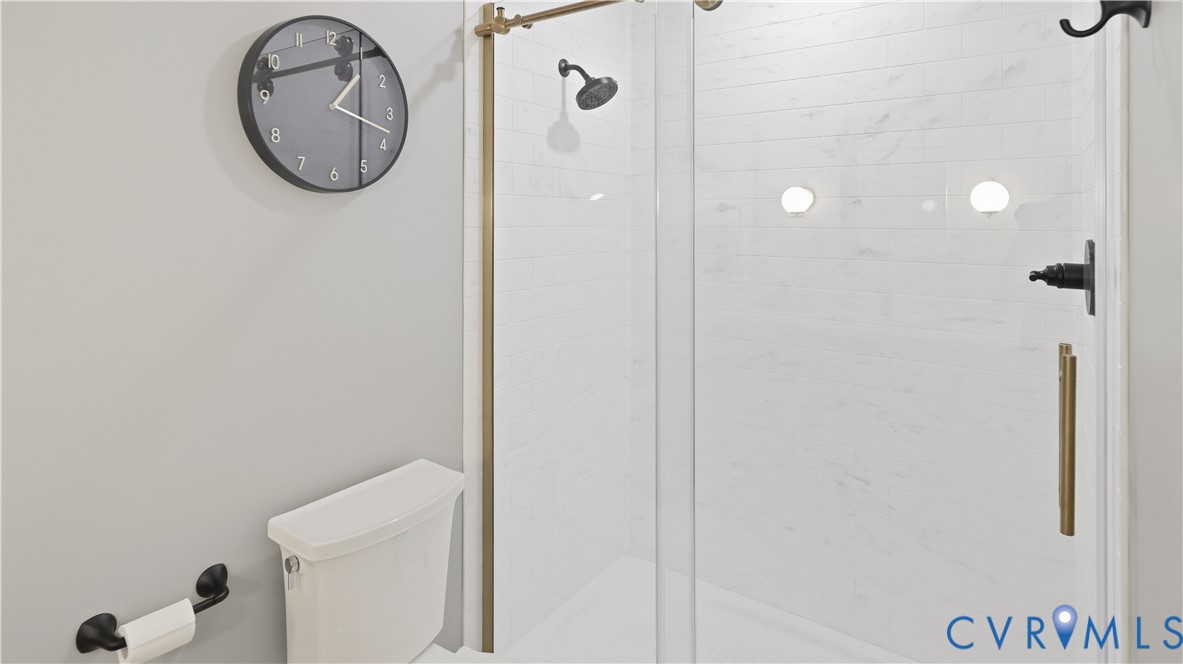 Glass-enclosed shower with a rainfall showerhead and matte black fixtures