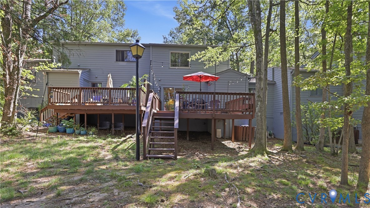 Expansive multi-level wood deck with wood railings, integrated exterior lighting, and direct exterior access