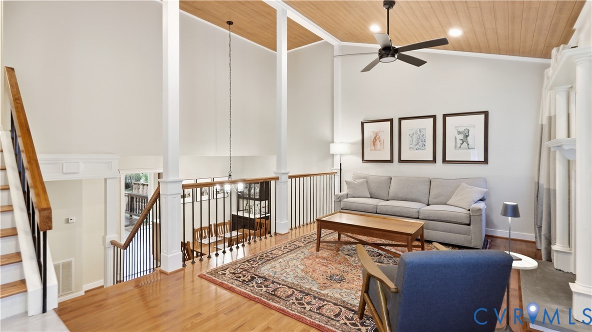Hardwood flooring, vaulted wood-paneled ceiling, white painted columns, iron balusters, and a ceiling fan Hardwood flooring, vaulted wood-paneled ceiling, white painted columns, iron balusters, and a ceiling fan