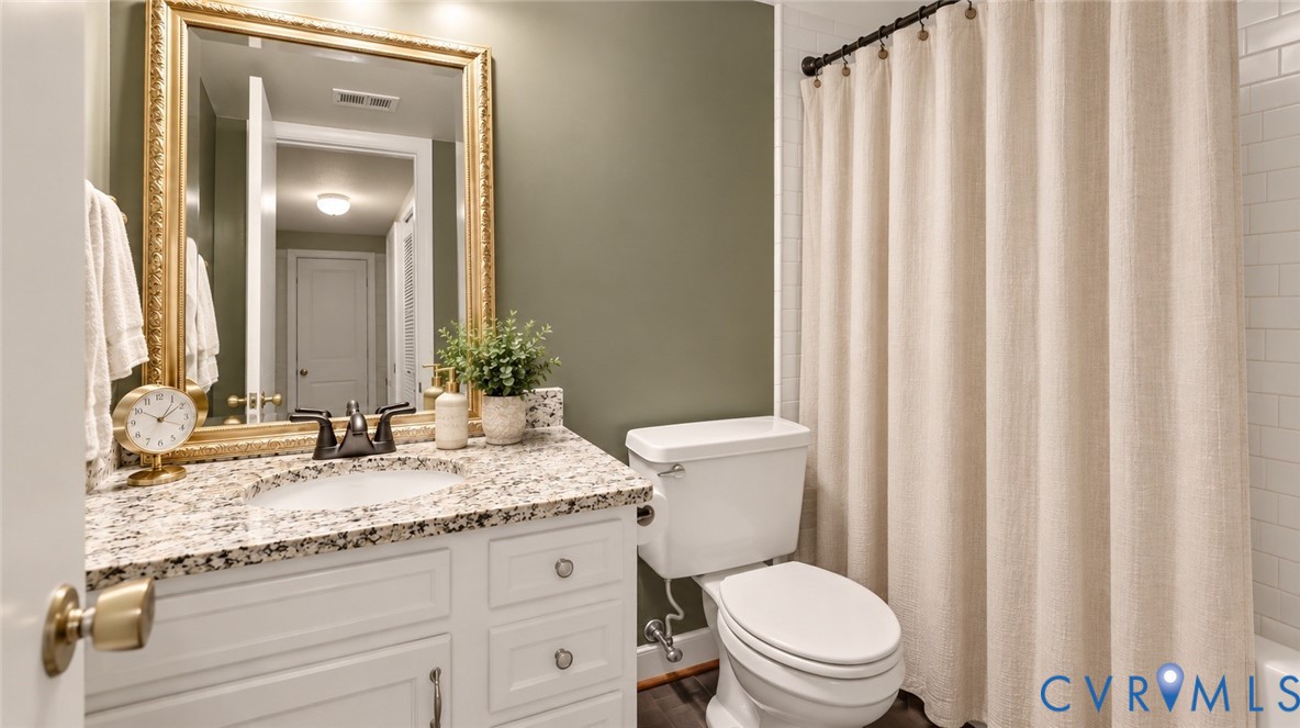 White vanity with a granite countertop, undermount sink, and dark bronze faucet