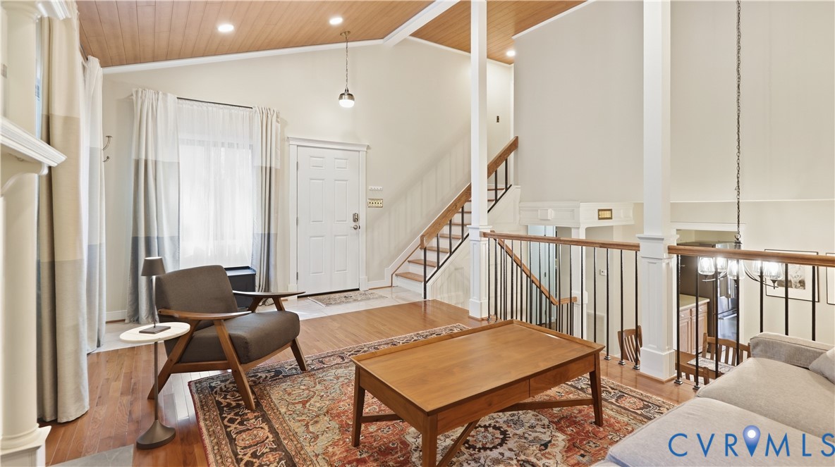 Vaulted wood-paneled ceiling, hardwood flooring, white paneled entry door, painted balusters with wood handrail, and recessed lighting Vaulted wood-paneled ceiling, hardwood flooring, white paneled entry door, painted balusters with wood handrail, and recessed lighting