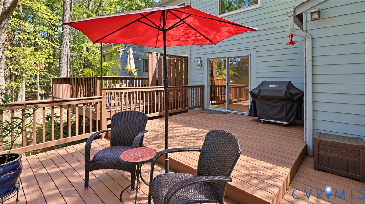 Multi-level wood-finish deck with wood railings, sliding glass door access, and exterior wall-mounted lighting