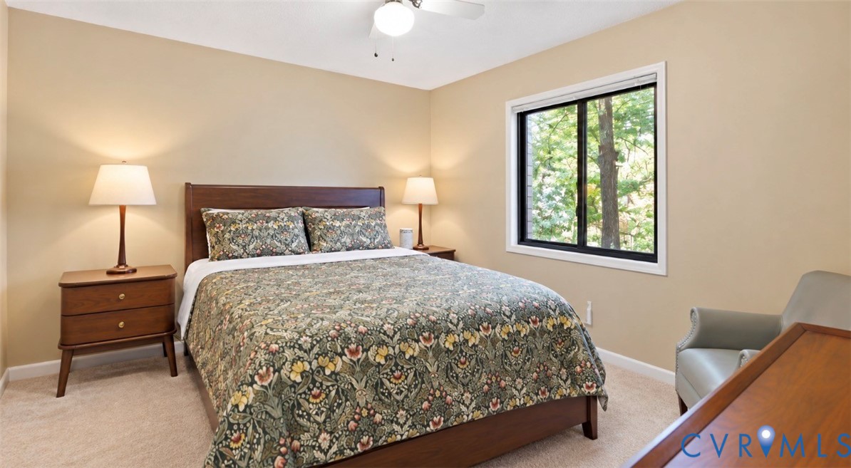 Neutral tone walls, carpet flooring, a single window with a black frame, and a ceiling fan
