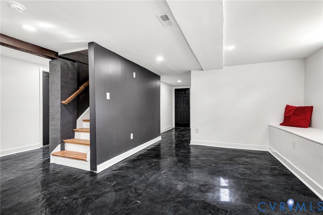 Polished dark flooring, recessed lighting, built-in bench seating, wood-finish staircase, and exposed structural beam