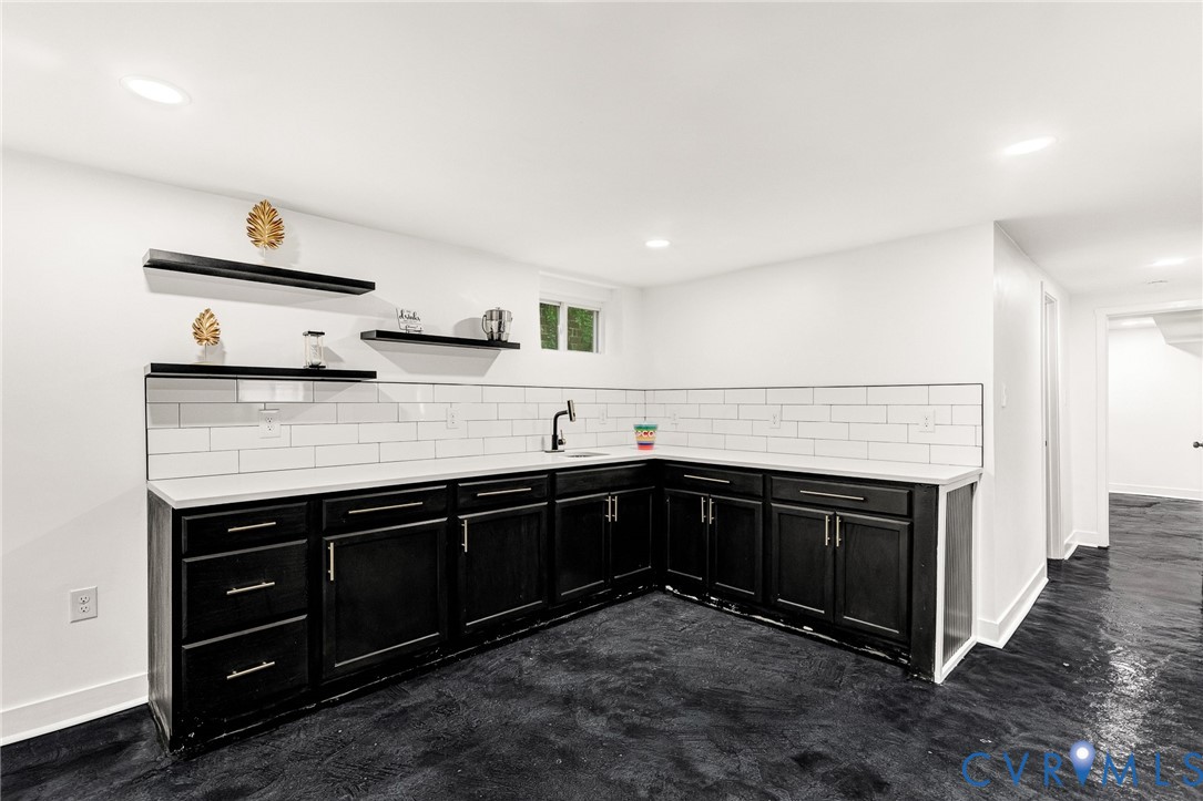 L-shaped cabinetry with dark finishes, integrated sink, and wall-mounted faucet
