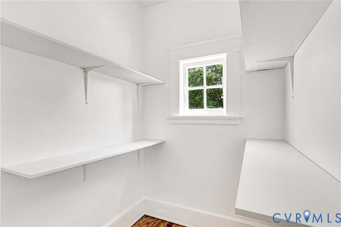 White built-in shelving, natural light from a double-hung window, and wood-finish flooring
