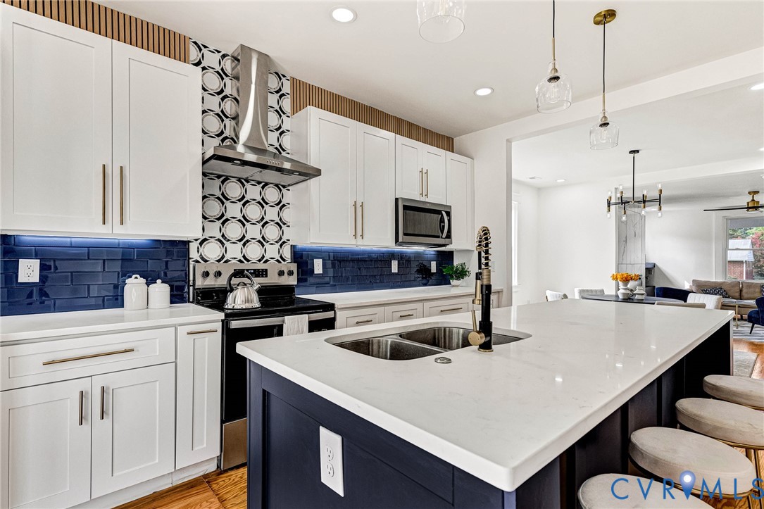 Gourmet kitchen featuring a large island, stainless steel appliances, contemporary cabinetry, and custom tile backsplash