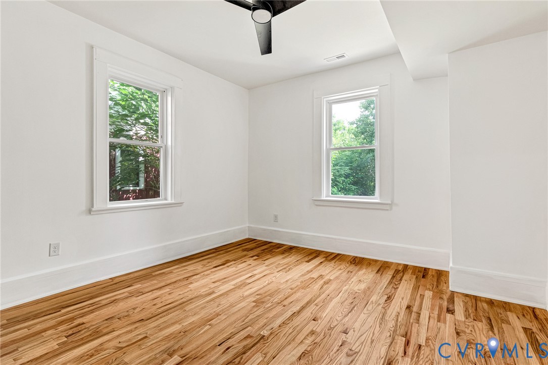 Wood-finish flooring, white walls, and a ceiling fan